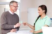 Patient am Empfangstresen mit Gesundheitskarte (Foto: BARMER GEK)