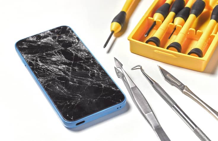 Handy mit Displayschaden und Reparatur-Werkzeug