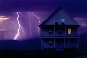 Im Hintergrund eines Landhauses sieht man zwei Blitze einschlägen.