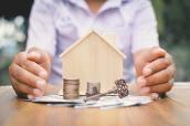 Haus mit Händen, Geld und Schlüssel