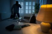 Einbrecher mit Handy, Geld und Lampe auf Tisch