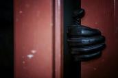 Einbrecher mit Handschuh an der Tür