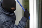 Einbrecher mit Stemmeisen versucht eine Fenster aufzubrechen.