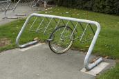 Einzelnes Vorderrad ist an einem Fahrradständer angekettet.