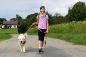 Junges Mädchen führt ihren Hund an der Leine Gassi.