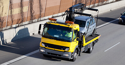 Ein gelber Abschleppwagen schleppt ein Auto ab.