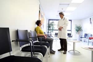 Patientin redet mit Arzt im Wartezimmer