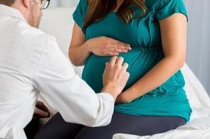 Arzt hört Schwangere mit Stethoskop ab.