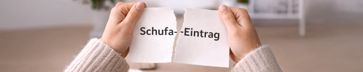 Zwei Hände zerreißen ein Stück Papier mit der Aufschrift Schufa-Eintrag