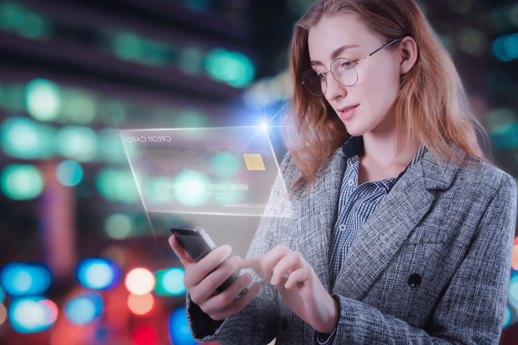 Eine Frau schaut auf ein Handy und ein Hologram einer Kreditkarte