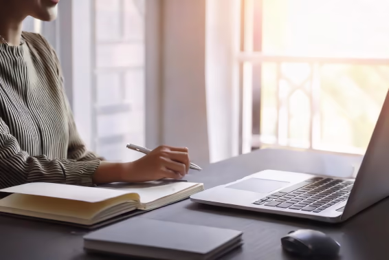 Eine Frau sitzt an einem Schreibtisch, und schaut auf einen Laptop