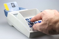 Mann gibt PIN-Zahl auf Kartenlesegerät ein.