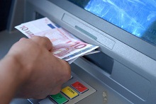 Mensch hebt Geld am Automaten ab