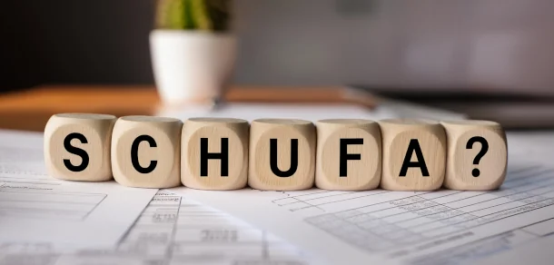 Welche Daten werden bei der Schufa gespeichert? Holzwürfel auf einem Schreibtisch mit dem Wort Schufa