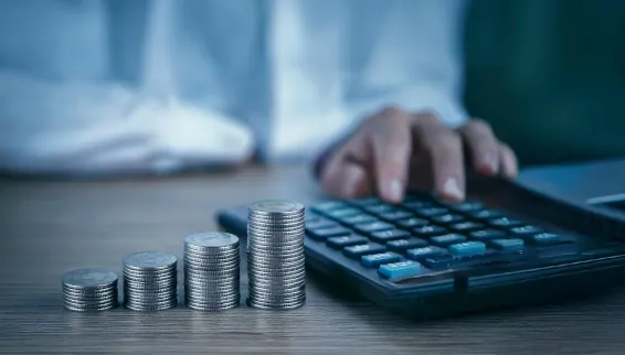 Ratgeber: Was Sie über Zinsentwicklung wissen müssen Eine Person sitzt mit einem Taschenrechner am Schreibtisch