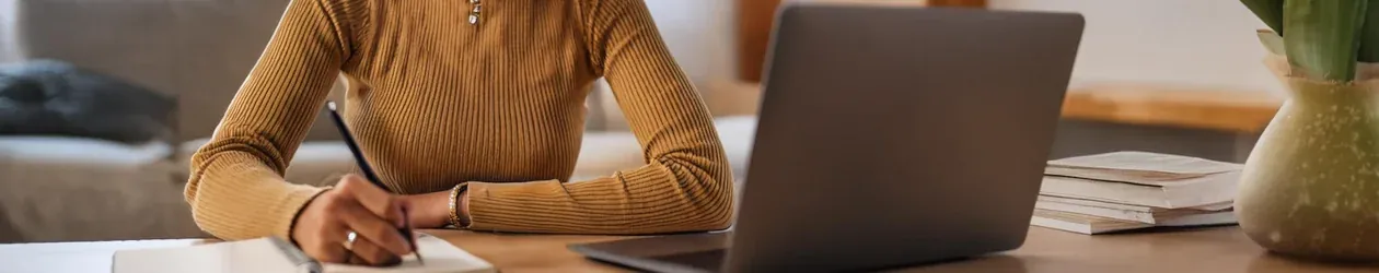 Girokonto Kündigen Person schreibt in ein Notizbuch und arbeitet an einem Laptop