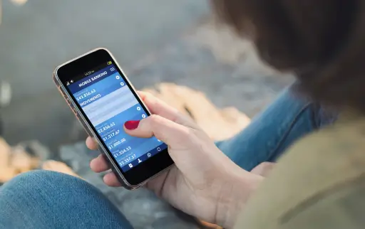 Frau schaut sich an Handy ihr Onlinebanking an
