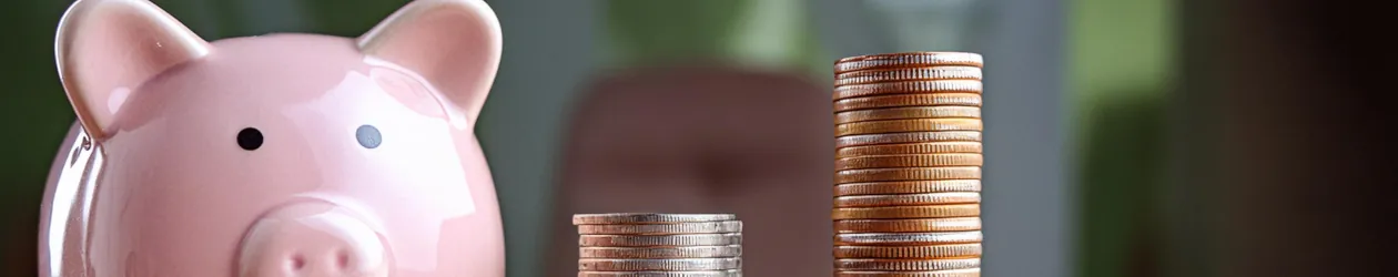 Sparkonto eröffnen – alles, was Sie wissen müssen Rosa Sparschwein neben gestapelten Münzen