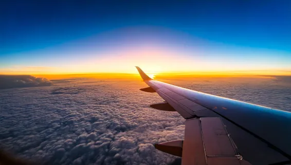 Flugzeugflügel über den Wolken bei einem Sonnenuntergang auf einer Weltreise