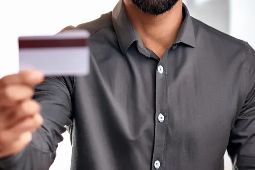 jetzt Kreditkarten mit Versicherungen vergleichen Mann hält Kreditkarte in seiner Hand