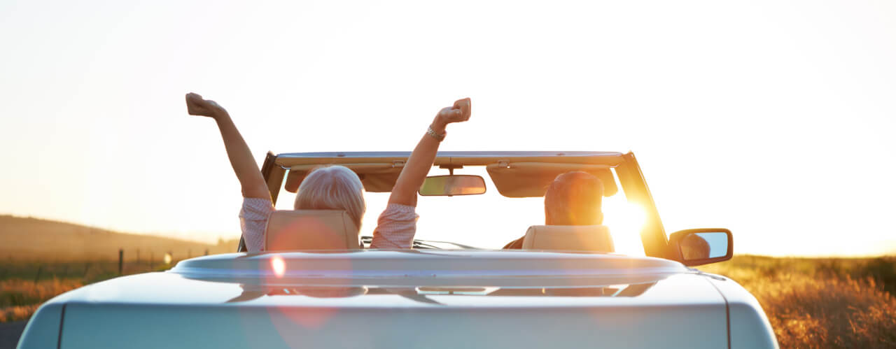 Pärchen fährt im finanzierten Cabrio dem Sonnenuntergang entgegen Pärchen fährt im finanzierten Cabrio dem Sonnenuntergang entgegen