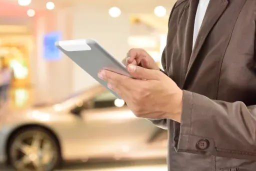 Finanziertes Auto verkaufen Eine Person tippt auf einem Tablet