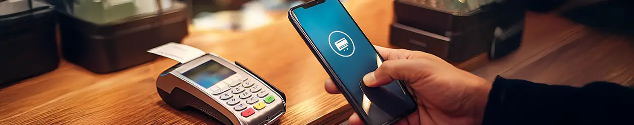 Mobile payment ist auf dem Vormarsch eine hand hält ein handy vor ein kartenlesegerät