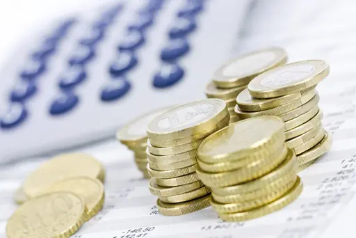 Was kostet ein Girokonto? Münzen liegen vor einem Taschenrechner