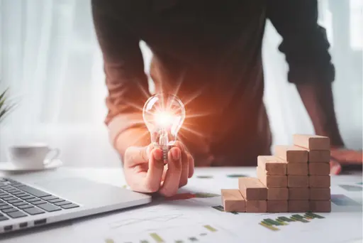 weitere Infos zur Kontoeröffnung Mann hält Glühbirne an einem Laptop hoch