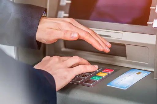 weitere Infos zum Dispokredit Mann gibt Pin an einem Bankautomaten ein