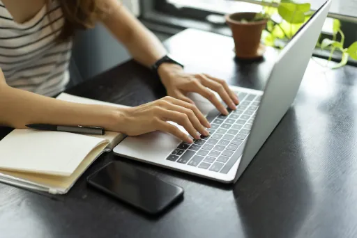 Frau sitzt am Schreibtisch vor ihrem Laptop