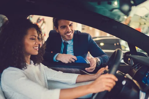 Auto finanzieren ohne Anzahlung Frau sitzt in einem Auto und ein Mann schaut durch das Autofenster