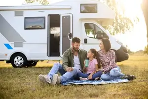 Eine Familie sitzt vor einem Wohnmobil