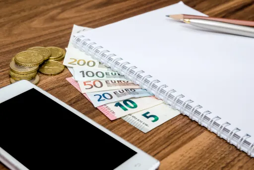 Bargeld mit Stift, Block und Smartphone