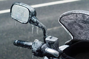 Eiszapfen hängen am eingefrorenen Lenker eines Mopeds.