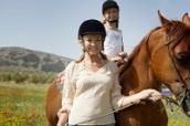 Eine Frau führt ein Pferd, auf dem ein Kind sitzt.