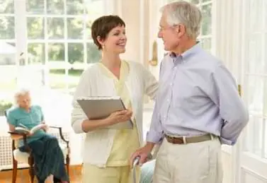 Betreuerin im Gespräch mit einem Senior im Altenheim