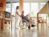 Mann im Rollstuhl im Pflegeheim mit Pflegerin