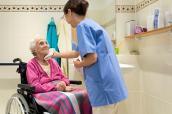 Ältere Frau im Rollstuhl mit Altenpflegerin im Bad