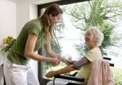 Pflegerin kümmert sich um Seniorin im Rollstuhl.