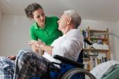 Frau betreut Senior im Rollstuhl.