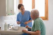 Altenpflegerin mit Senior im Badezimmer
