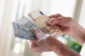 Die Hände einer Seniorin halten Geldscheine.