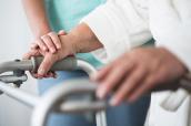Eine Person stützt sich auf einen Rollator.