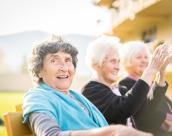 Drei Seniorinnen sitzen draußen auf einer Bank.