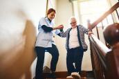 Pflegerin hilft Seniorin die Treppe hinunter