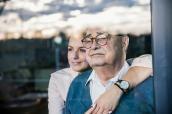Senior sitzt mit junger Frau an einem Fenster