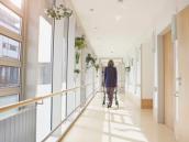 Seniorin mit Rollator auf einem Gang im Pflegeheim