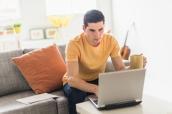 Junger Mann sitzt vor Laptop