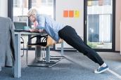 Angestellte macht Push-ups am Schreibtisch.